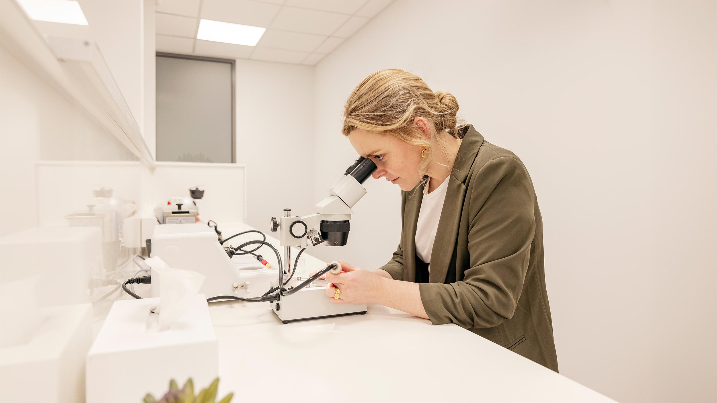 Vrouw die door microscoop kijkt voor de reparatie